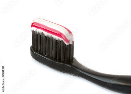 Charcoal toothbrush with striped tooth paste on a white backgrou