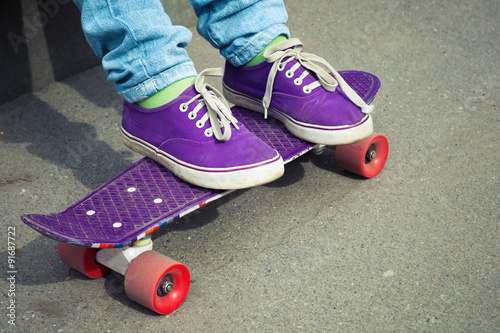 Feet in blue jeans and gumshoes with skateboard