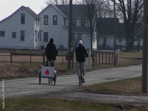 young people on bikes pull two very young kids in a child carrier.