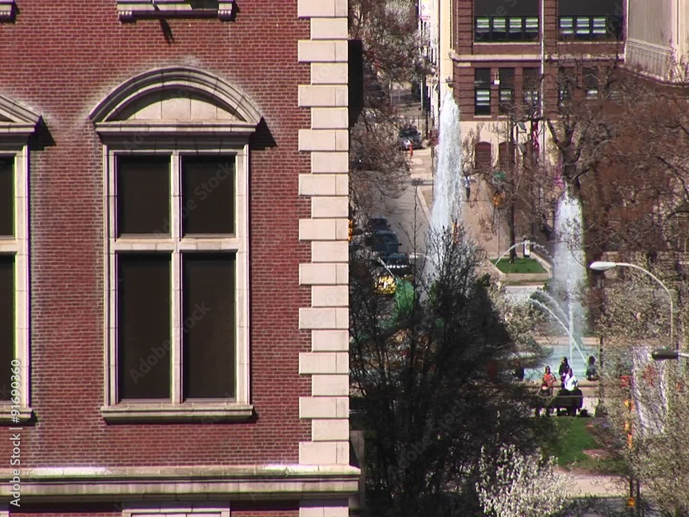 A look at a downtown park with fountains with a classical old building corner in the foreground. A look at a downtown park with fountains with a classical old building corner in the foreground.