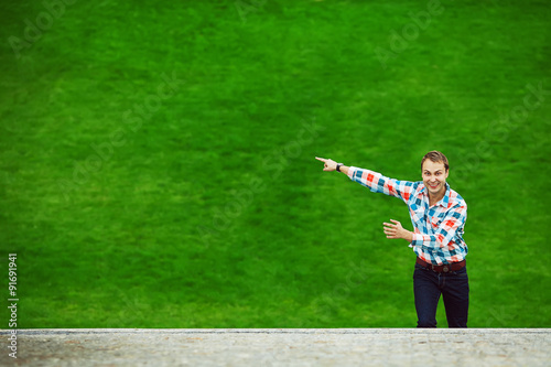 Portrait of happy young happy man standing near green lawn