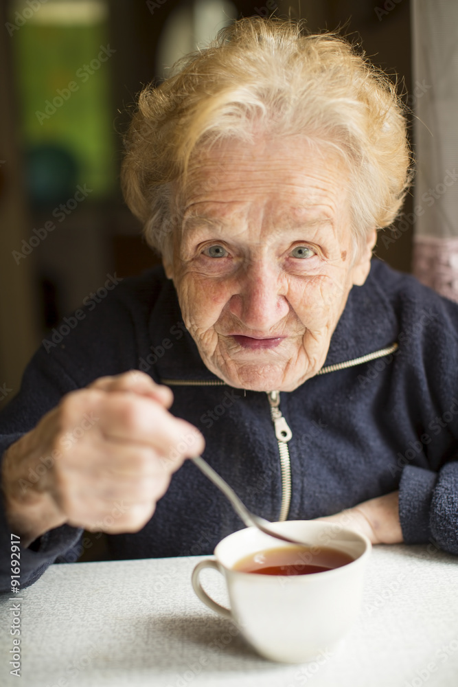 Grandmother sitting at the table drinking tea from a Cup. Grandmother sitting at the table drinking tea from a Cup.