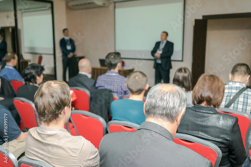 Meeting in a conference hall. Two speakers delivering presentation near the screen.