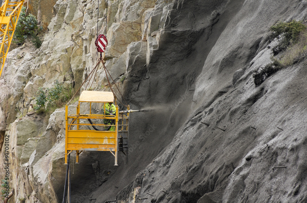 buider worker in crane vehicle sprayed concrete shotcrete in highway slope for prevent collapse