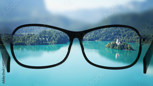 Put the glasses for the different, better view. Looking at the lake with the mountains.