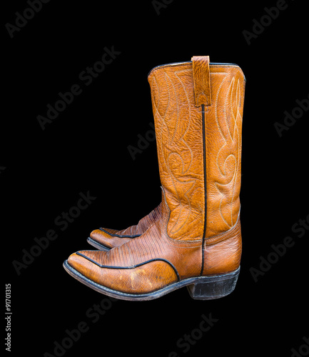 A pair of brown cowboy boots isolated on a black background