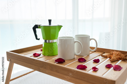 Breakfast tray with coffee on bed decorated roses