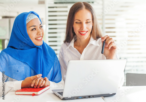 Fotografie European woman and asian muslim woman working together on same project