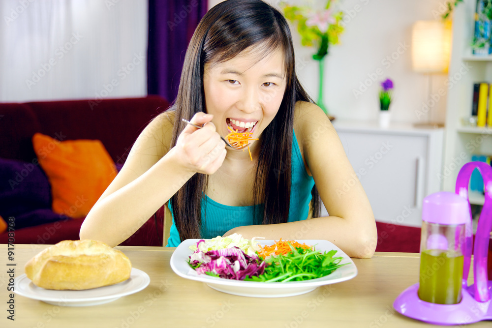 Happy asian girl eating salad at home Happy asian girl eating salad at home