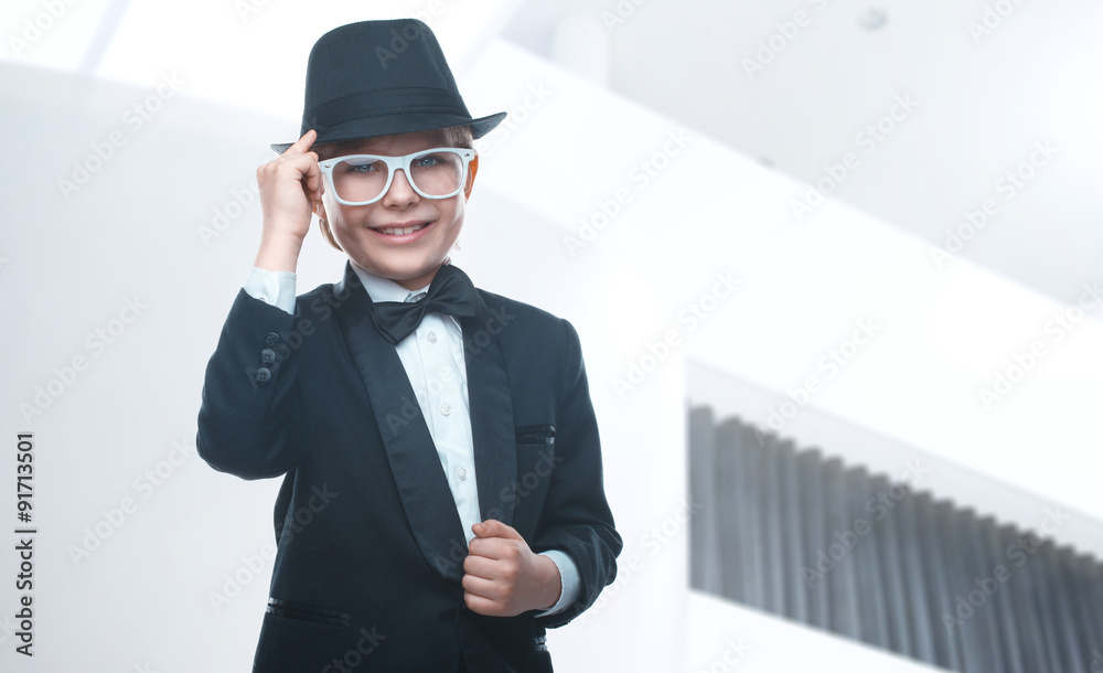 Beautiful little boy in a nice tuxedo and sunglasses goes to school. Stylish baby laughing and looking at the camera. Children portrait Beautiful little boy in a nice tuxedo and sunglasses goes to school. Stylish baby laughing and looking at the camera. Children portrait