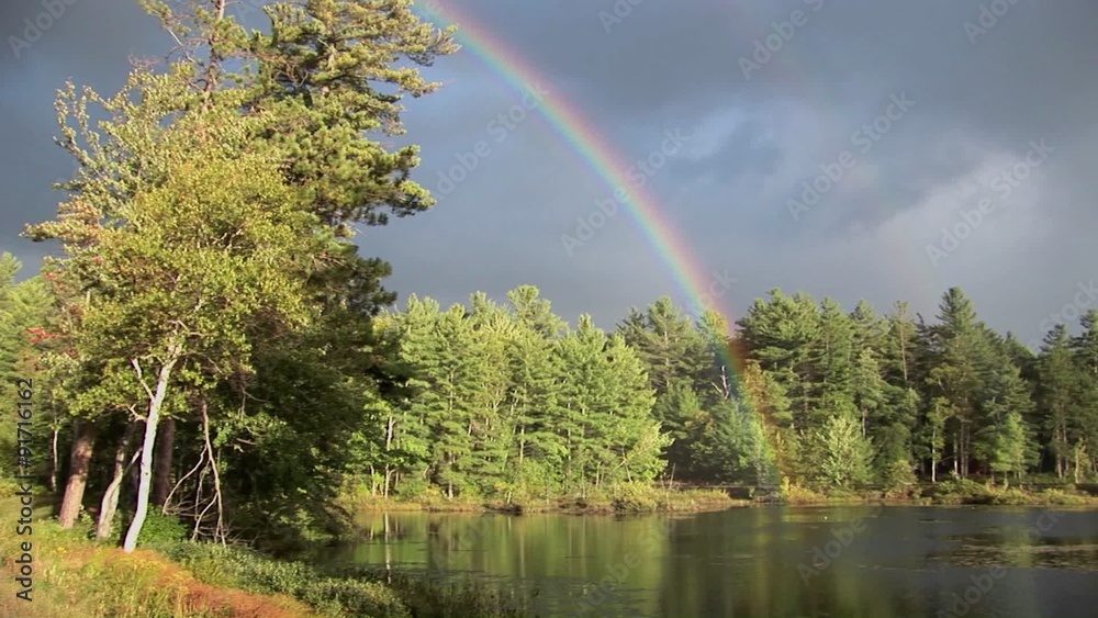 A rainbow over a forest and near a lake in Rural Maine. A rainbow over a forest and near a lake in Rural Maine.