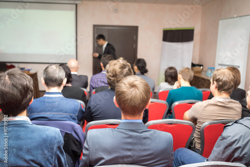 Speaker on the podium and rear view of the people at the conference hall. © elen31