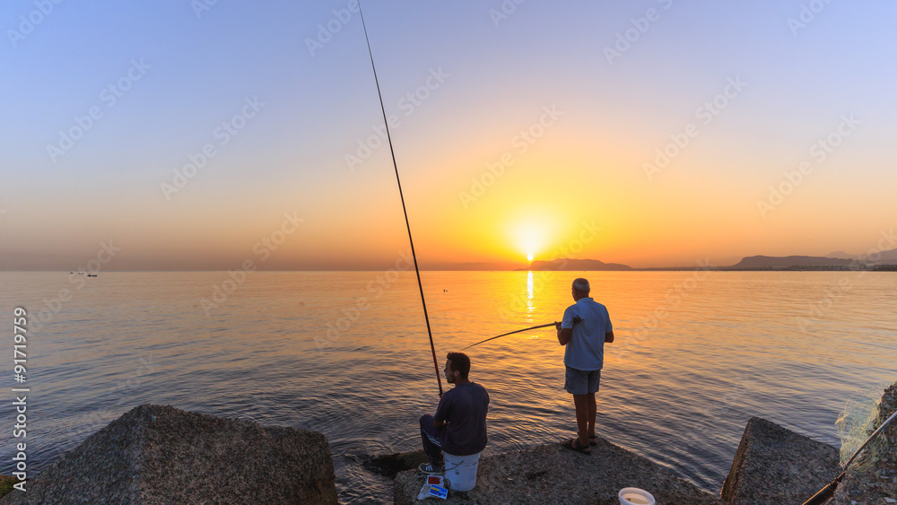 Young and older italien men fishing in the sunrise on Sicily