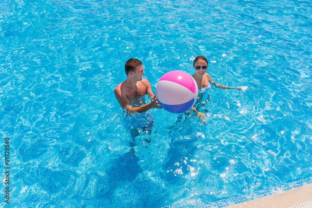 Young Couple in Swimming Pool with Beach Ball