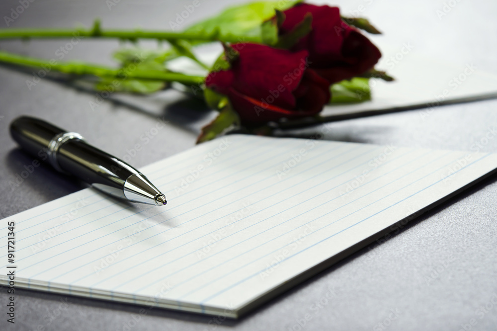 Pen lying on blank paper cards with rose background Pen lying on blank paper cards with rose background