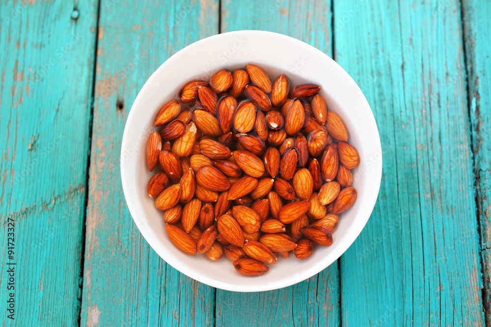 Wet raw almonds on turquoise wooden table Wet raw almonds on turquoise wooden table