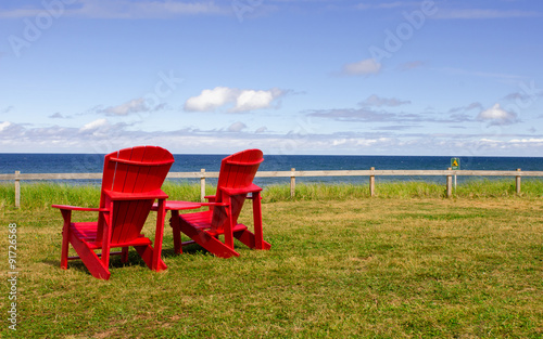 two red Adirondack chairs with a view