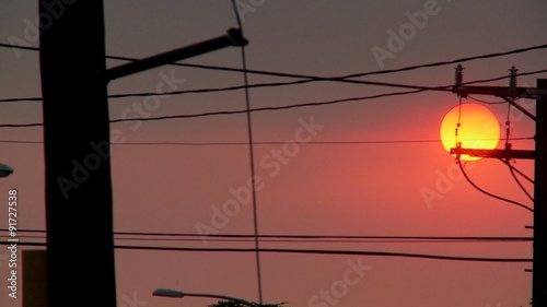 A orange ball of sun sets behind power lines during fire season in California. photo