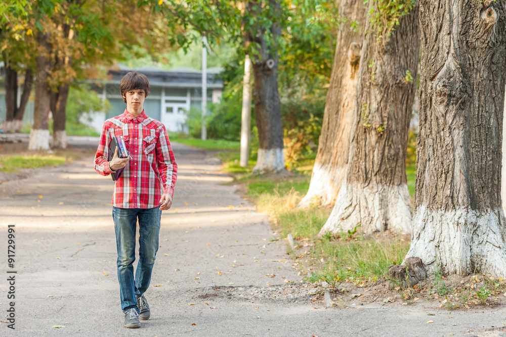 young student man holding a book and tablet against a city background young student man holding a book and tablet against a city background
