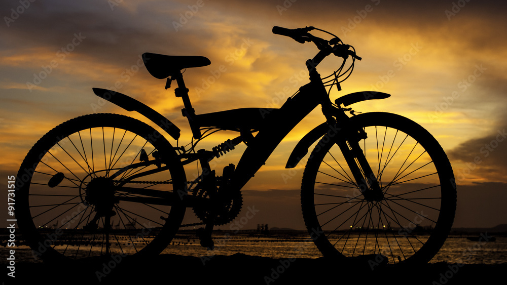 Obraz premium Silhouette of mountain bike with sunset sky beside sea, Thailand