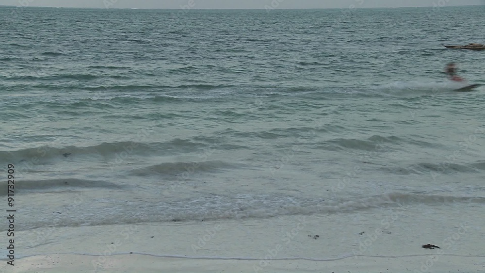 Waves roll in as a kite boarder passes in the distance. Waves roll in as a kite boarder passes in the distance.