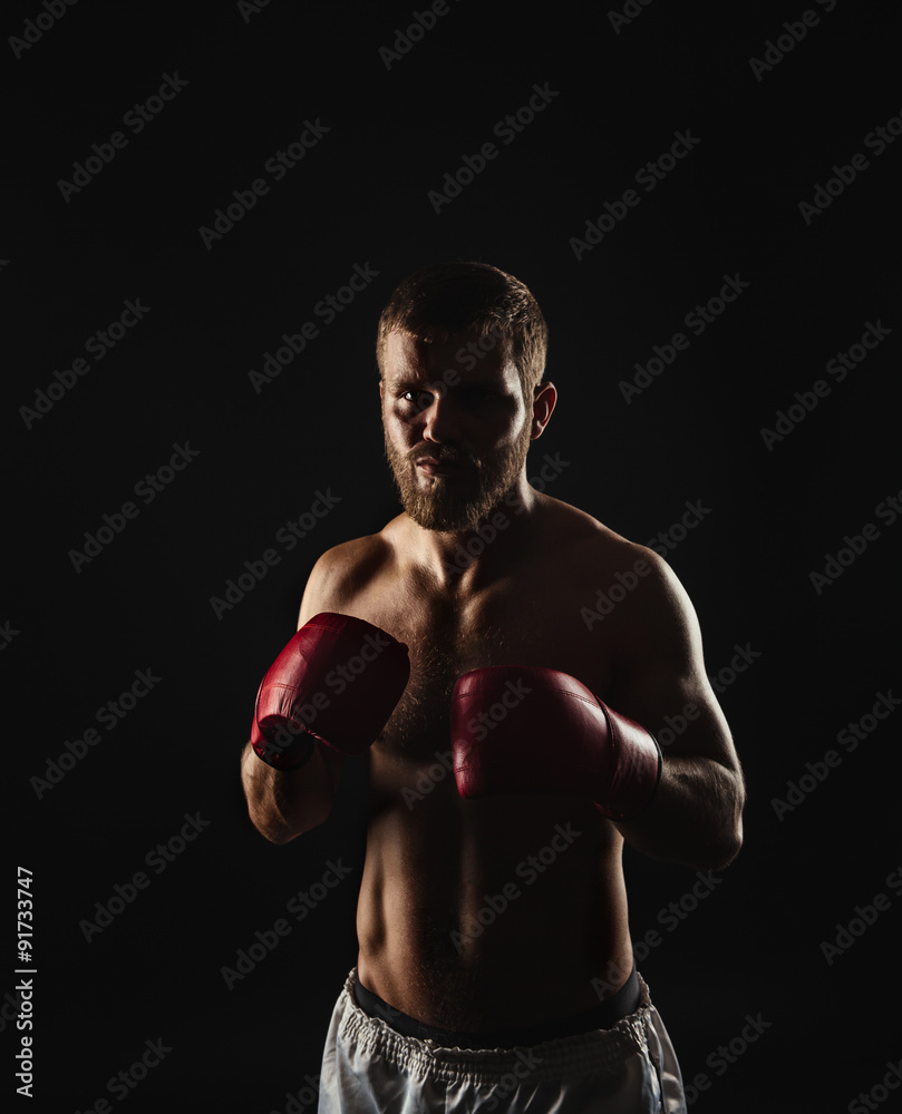 Athletic bearded boxer with gloves on a dark background Athletic bearded boxer with gloves on a dark background
