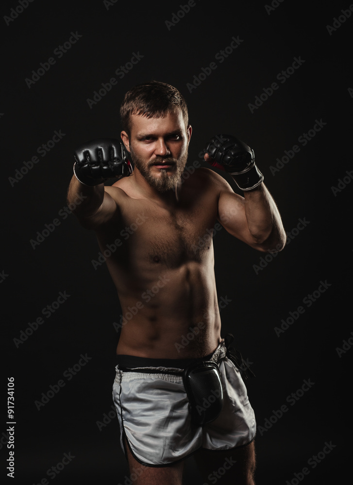 Athletic bearded boxer with gloves on a dark background Athletic bearded boxer with gloves on a dark background
