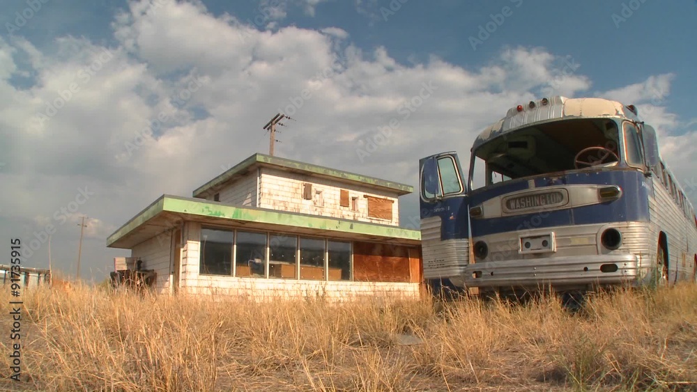 An abandoned Greyhound bus in a field.