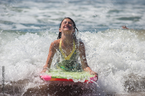 Girl child feeling the ocean surge as she rides the boogie board. © motionshooter