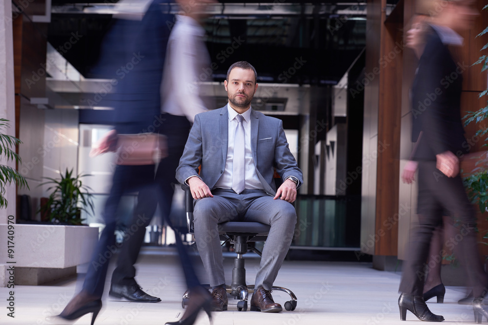 Obraz premium business man sitting in office chair, people group passing by