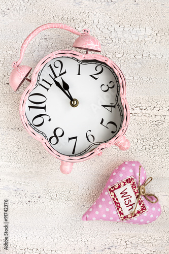 Retro pink clock and soft pink heart with word WISH on wooden ba photo