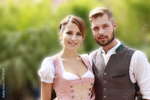 Glückliches bayrisches Paar in Tracht mit Bier und Brezn photo