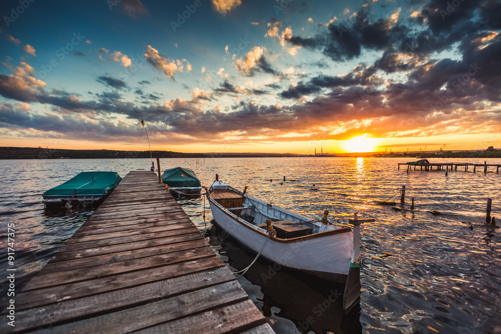 Obraz premium Peaceful sunset with dramatic sky and boats and a jetty