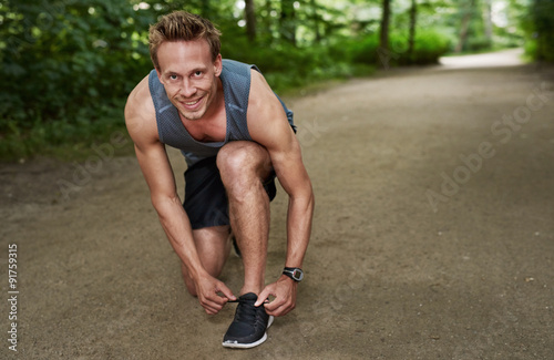 Smiling Fit Man Fixing his Shoelace at the Park © Flamingo Images