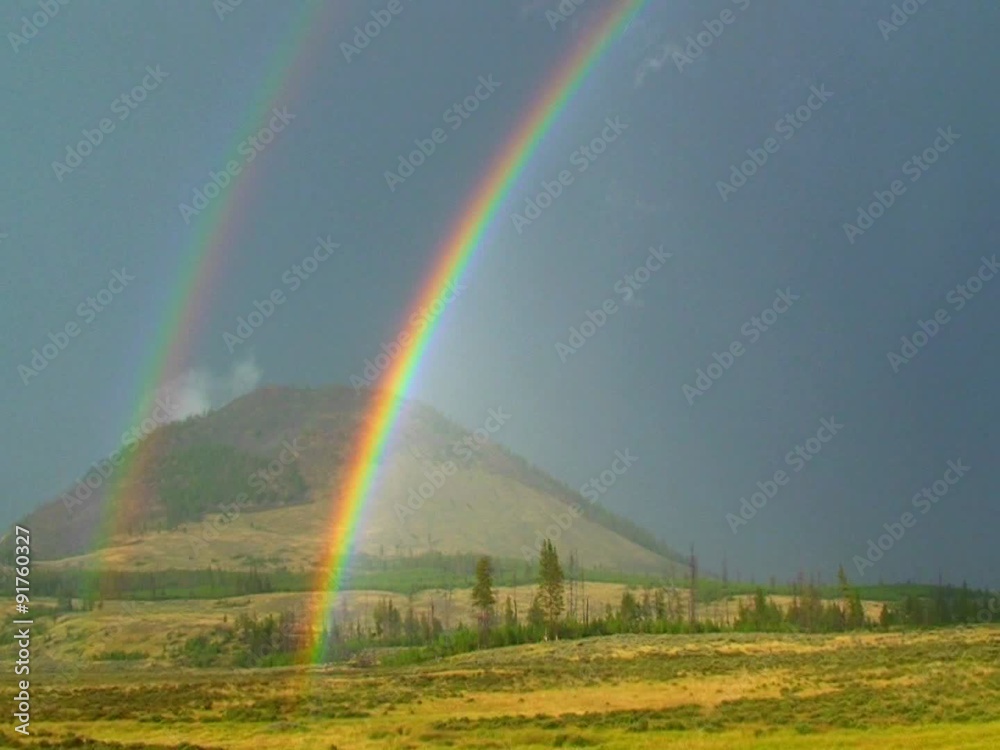 A double rainbow shines over a field. A double rainbow shines over a field.
