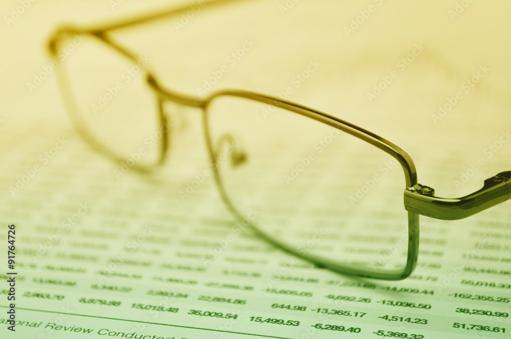 Glasses on business graph, financial concept Glasses on business graph, financial concept