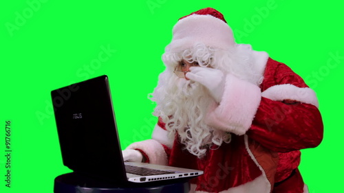 Santa Claus with a laptop chroma key (green screen). Santa uses the laptop isolated on green

