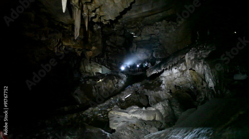 People explore a dark cave with flashlights. photo