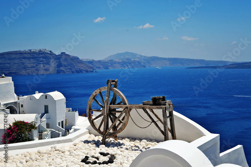 View of the Santorini caldera, seen from the streets of the famous village of Oia. A wooden decoration can be observed on a house roof.