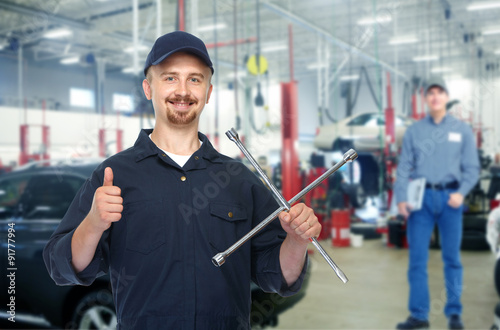 Smiling repairman with tire wrench.