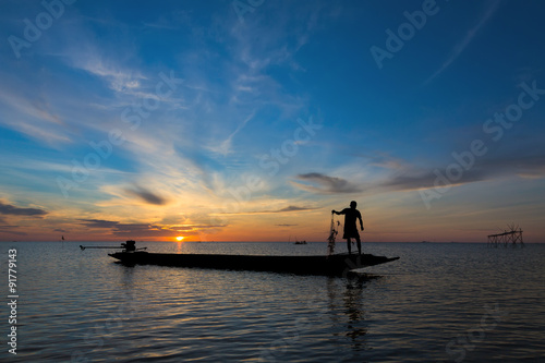 A Silhouette Fisherman Catching Fish from square dip net at Pak Pra Canal in early morning during golden sunrise moment