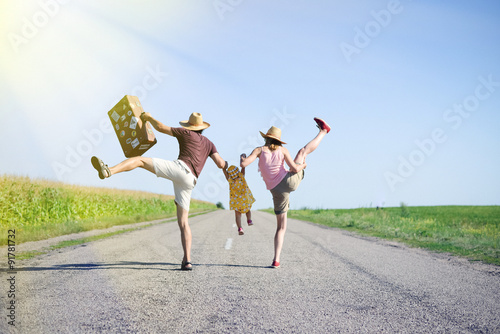 Happy family jumping and having fun on road in summer