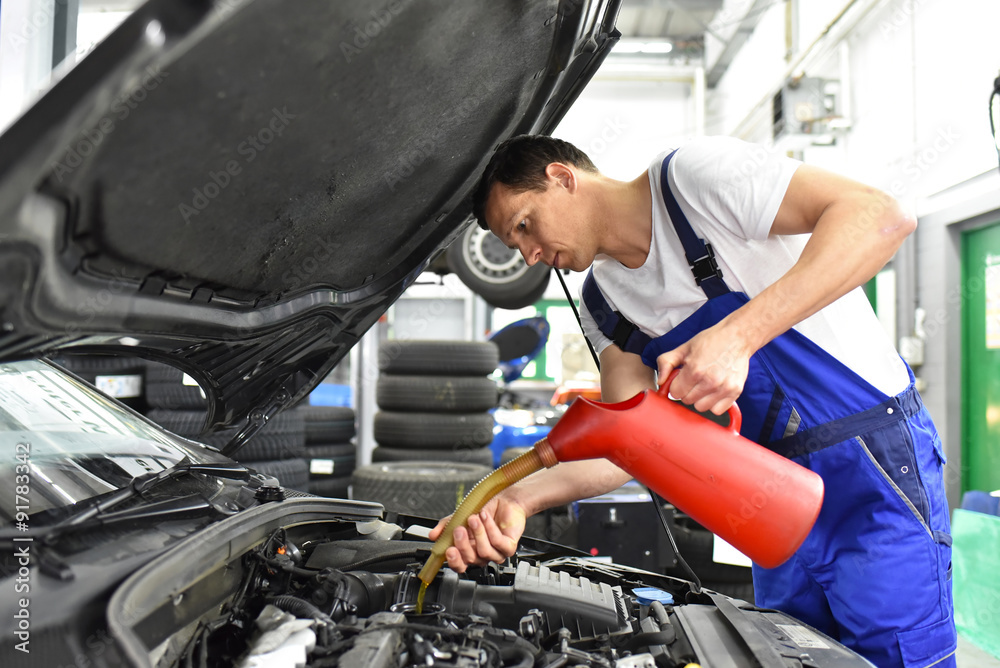 Mechaniker füllt Motoröl im Auto in einer Werkstatt nach // oil change in a car workshop - garage