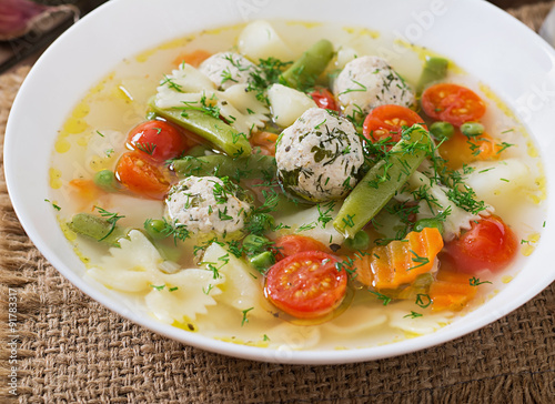 Diet vegetable soup with chicken meatballs and fresh herbs in bowl