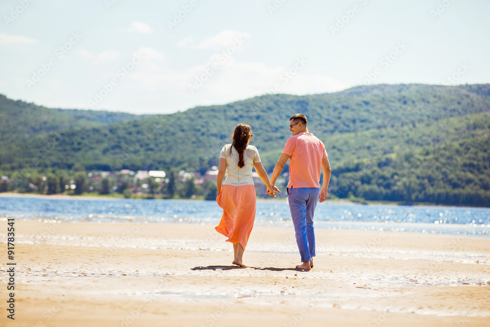 Happy young couple is having fun at bright sunny beach background.