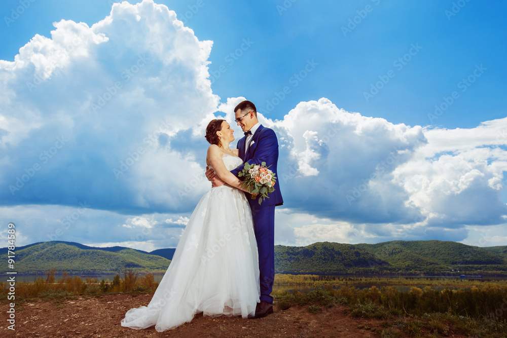 Beautiful elegant young wedding couple is embracing at hill