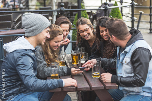 Group of friends looking at smart phone at pub