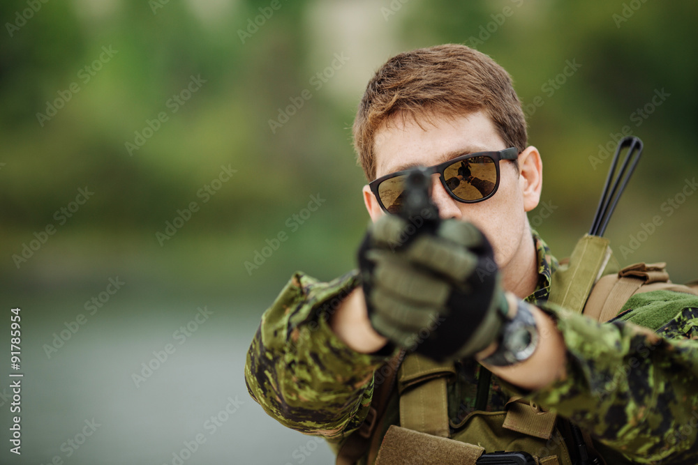 young soldier aiming and shooting with a pistol