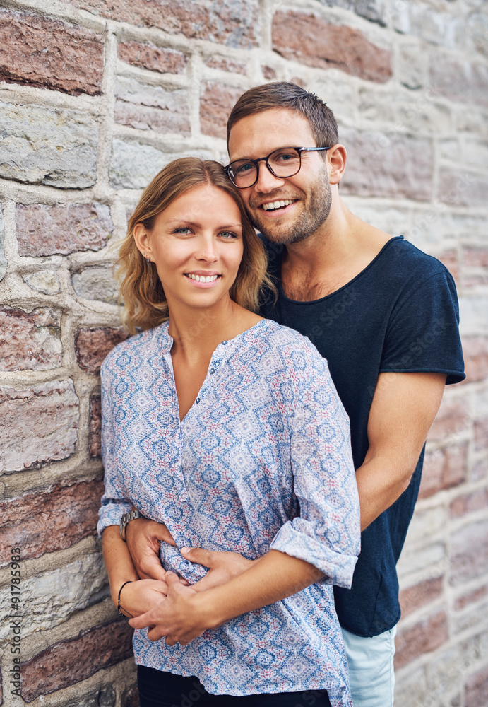 Sweet Couple Against Wall and Smiles at Camera