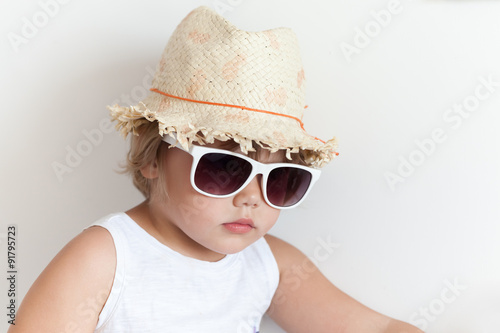 Cute Caucasian little girl in straw hat and sunglasses